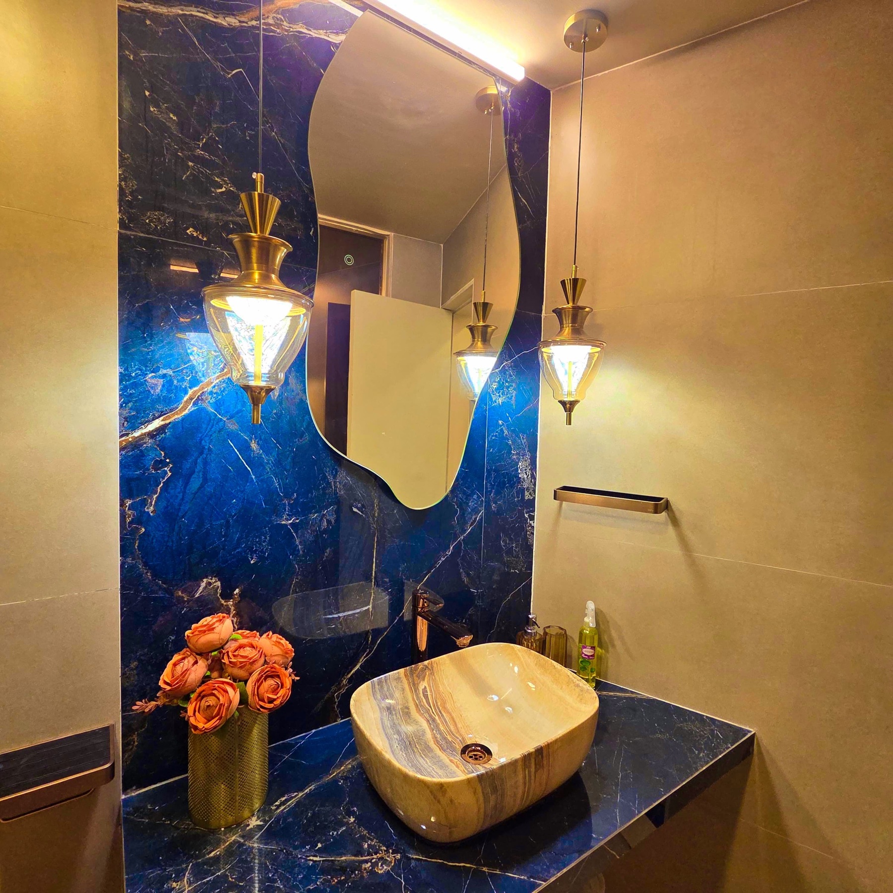 Bathroom in lapis blue marble with an onyx basin and brass pendant lights