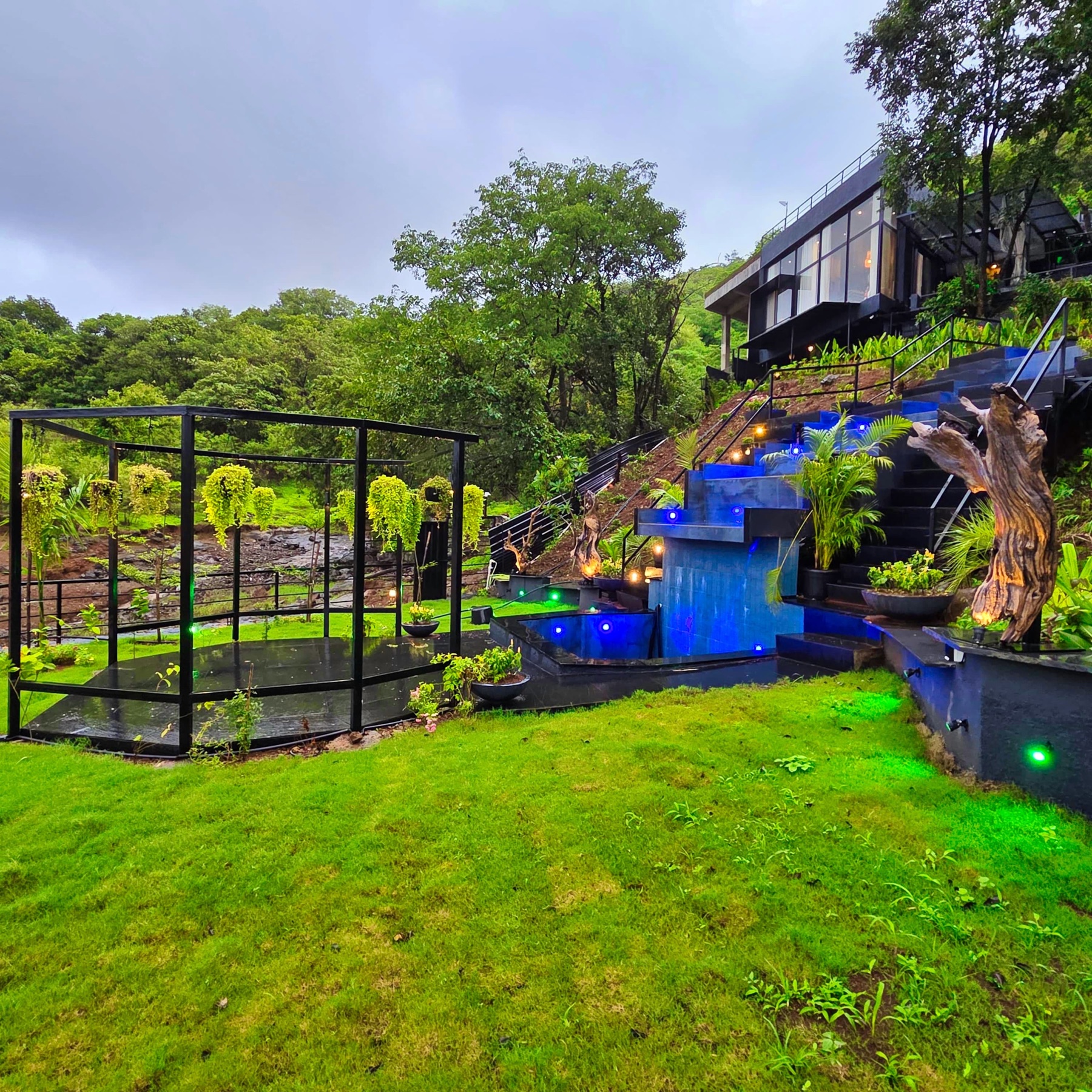 The stepped cascade and glass pergola on the lawn below the villa in monsoon