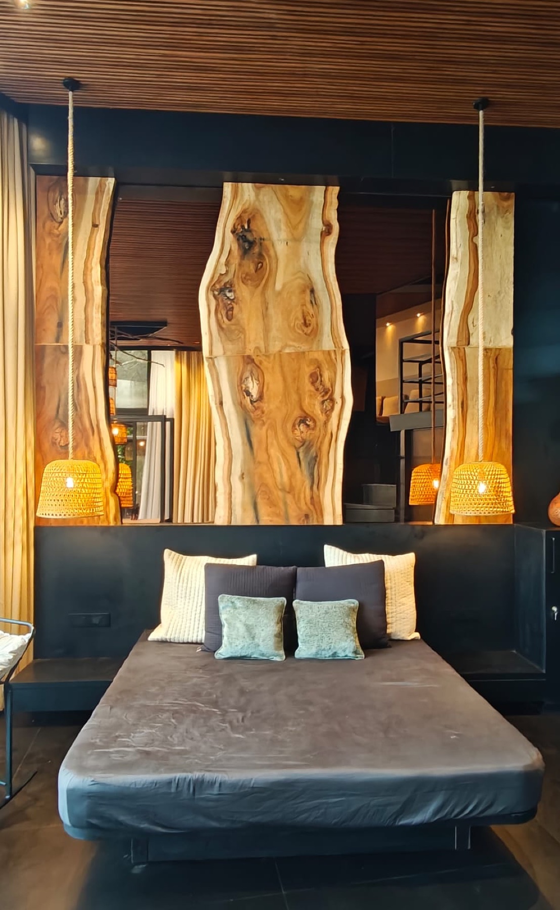 Villa bedroom with a live-edge timber headboard wall and woven pendant lights